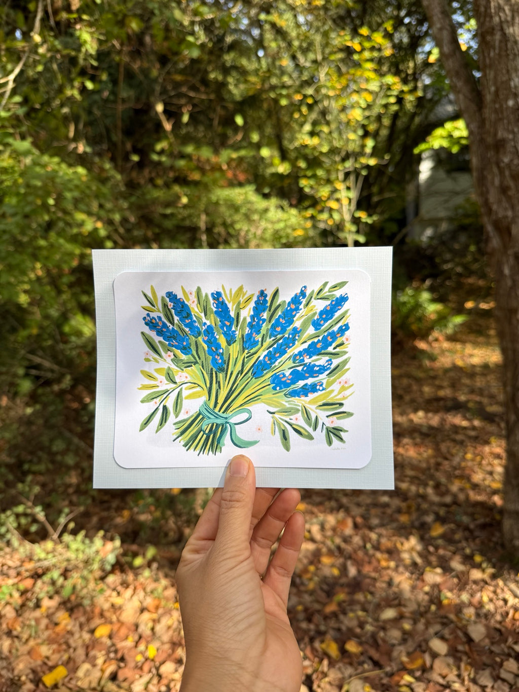 Blue botanical art print held outdoors
